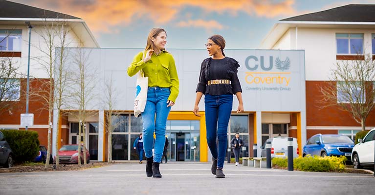 Two female students talking whilst walking away from Mile Lane