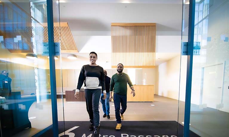 Three people walking through the door of the CU London building