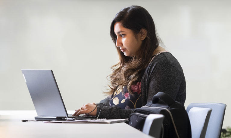 A girl sat at a desk on her laptop