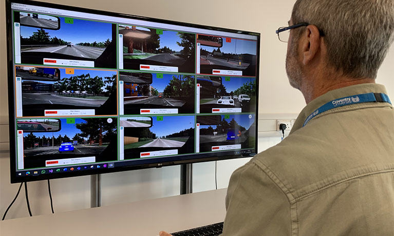 Person monitoring self-driving cars on a screen