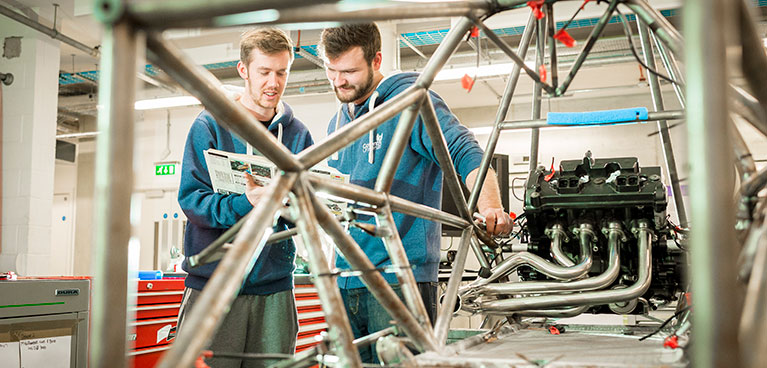 Chassis fabrication facility Motorsport students welding in a laboratory while reading through documentation