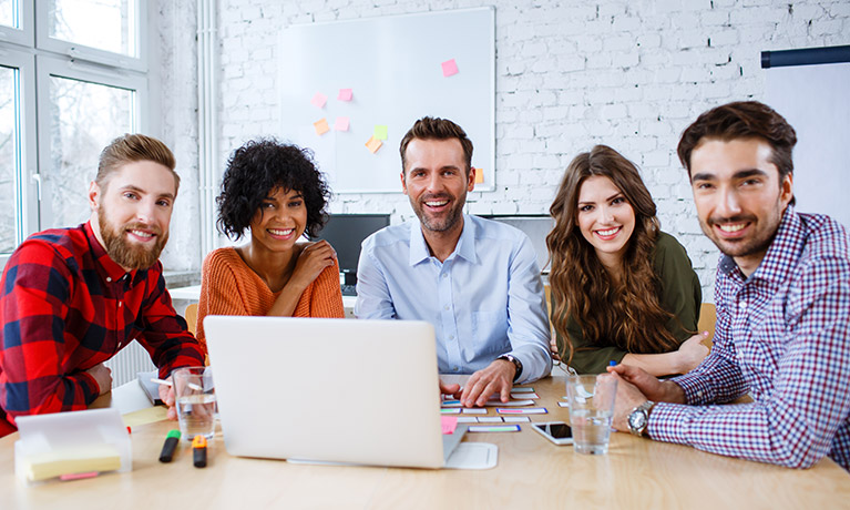 A group of professionals gathered around a laptop