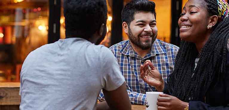 Three students sitting in the outside area of the bar socialising