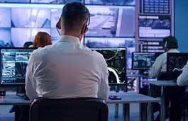 emergency worker studying multiple monitors in a control room 