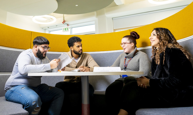 Four students sat around a table in an open study area booth at CU Coventry