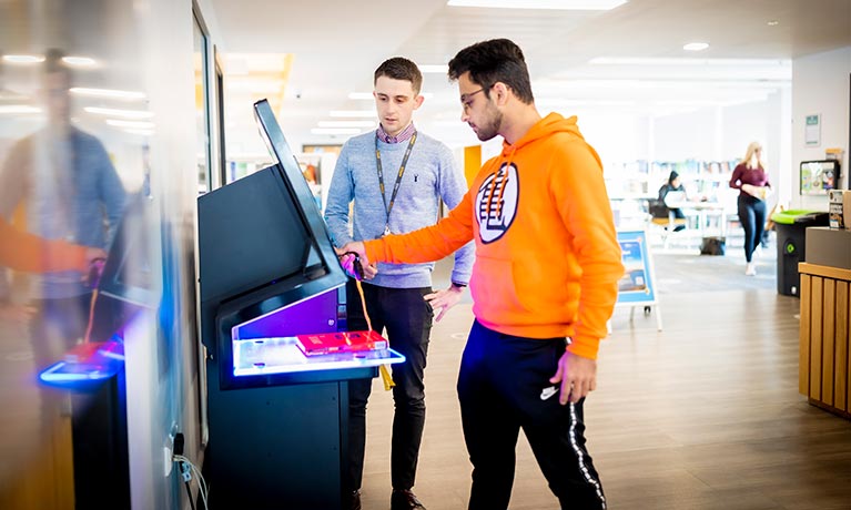 A member of staff helping a student on a touchscreen device