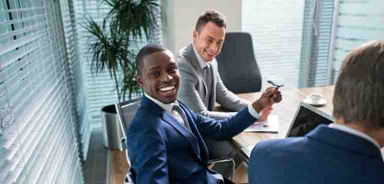 men in suits sat in an office room and smiling