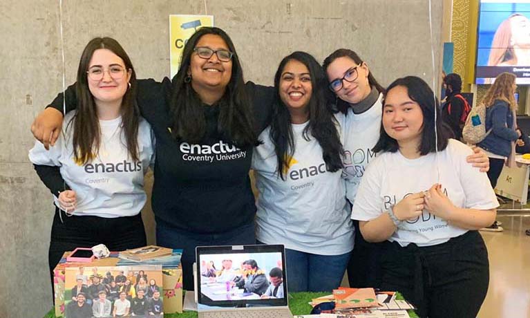 group of students from the Enactus Committee smiling at a fair