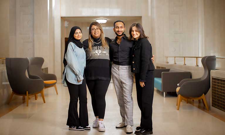 Four students with their arms around each other smiling