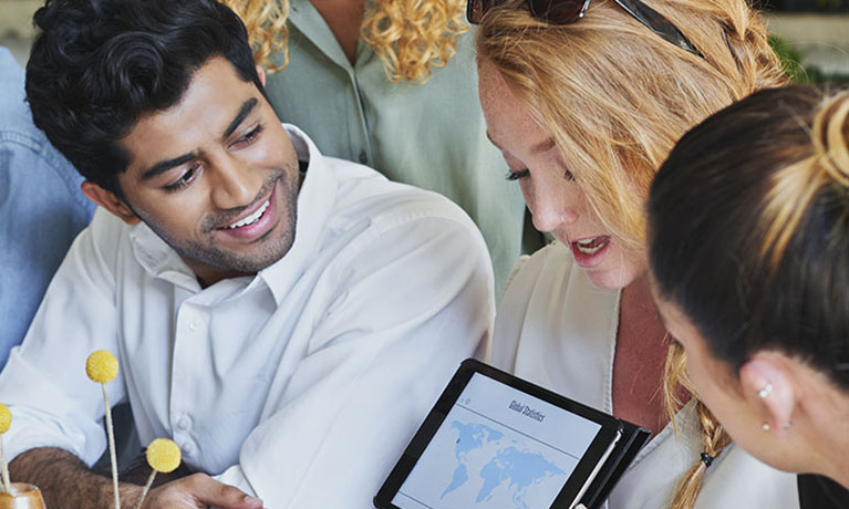 three people looking at an iPad, smiling