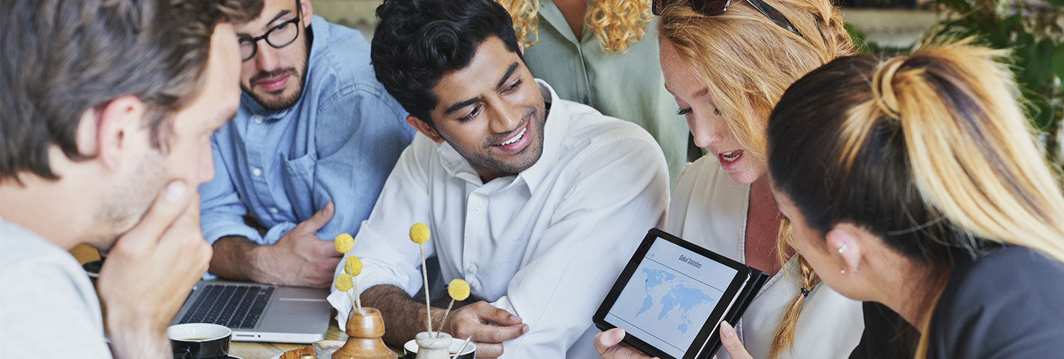 group of people sat looking at an iPad screen held by someone