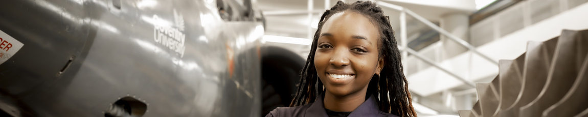 An international student working on a Harrier Jet, smiling at the camera