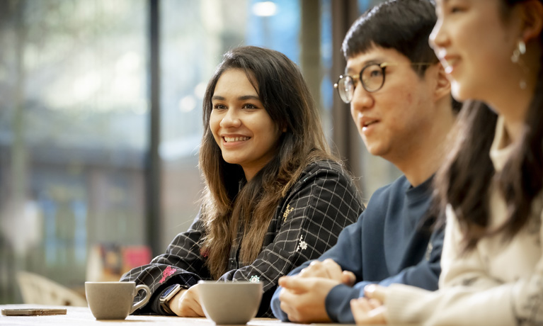 Three international students sat at a table in The Hub cafe
