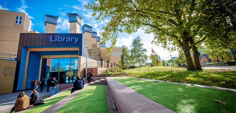 Library People walking in front of a building which has a big library sign