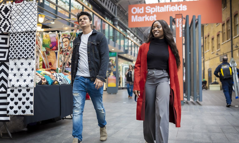Two Coventry University London students walking through the bright and diverse Spitalfields indoor market