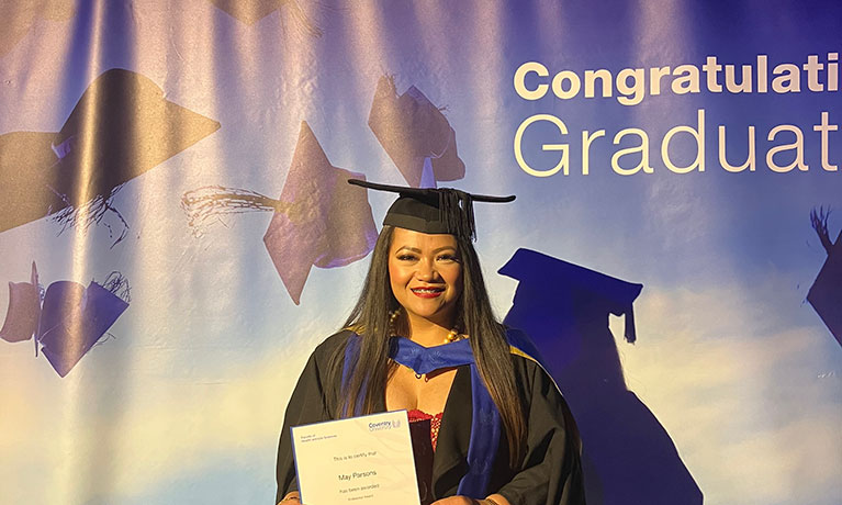 May Parsons smiling in a graduation gown and cap