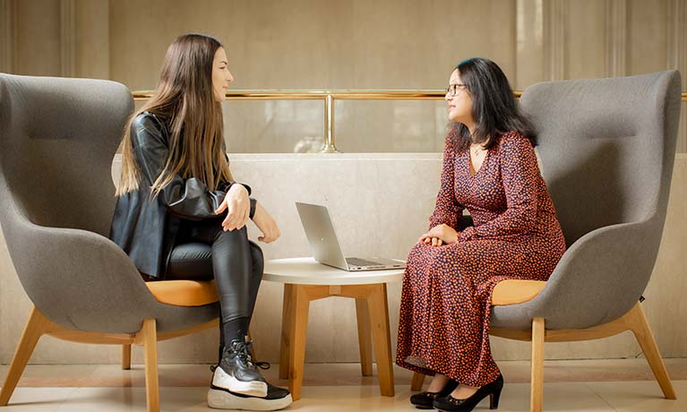 Two students sat opposite each other talking