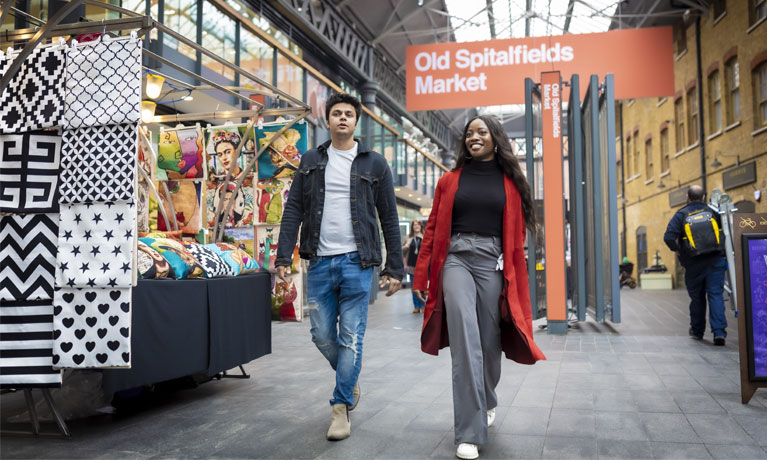 Two students walking through the colourful Spitalfields Market