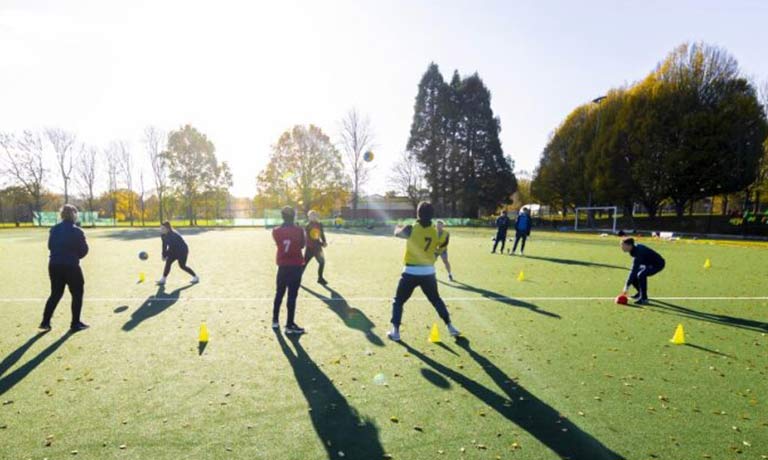 Students training on a football pitch in evening sun