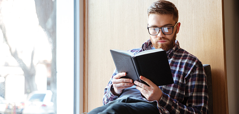 student sat on a window sill, reading
