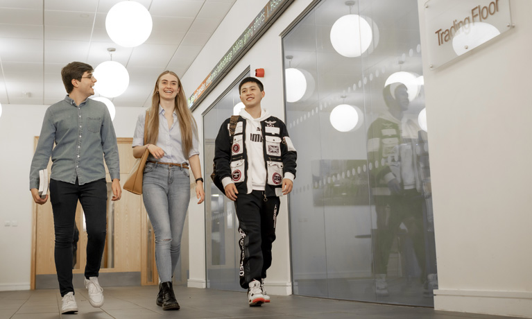 Three students walking outside the trading floor 