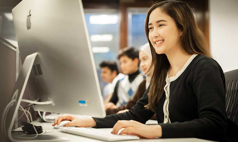 Students sitting in front a row of monitors 