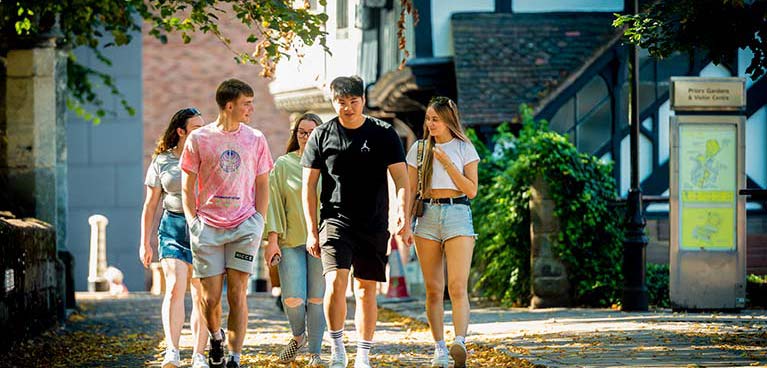 Group of new students walking together in university grounds on sunny day