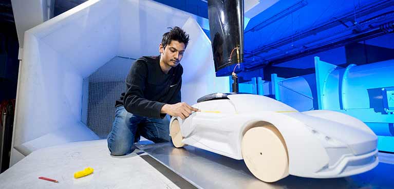 Wind tunnel facilities Young student polishing a model car